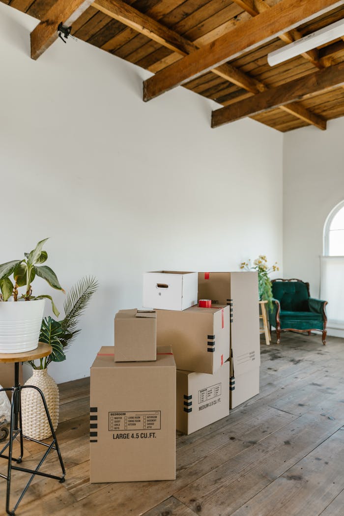 experience-img A spacious room with wooden floors and stacked cardboard boxes, ideal for moving concepts.